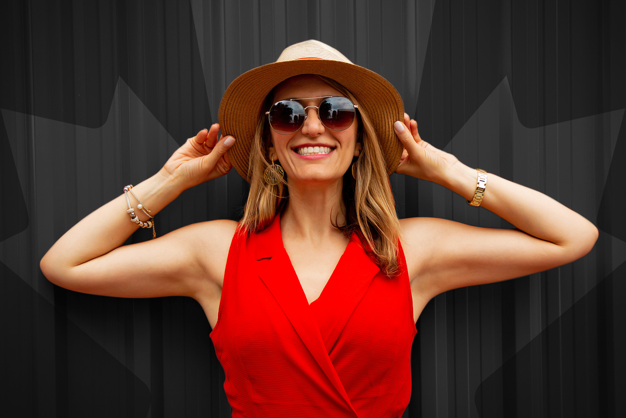 Smiling woman wearing sunglasses, a hat, and a red top posed against a dark backdrop with Canadian maple leaf accents for a Whistler corporate travel promotional video. 