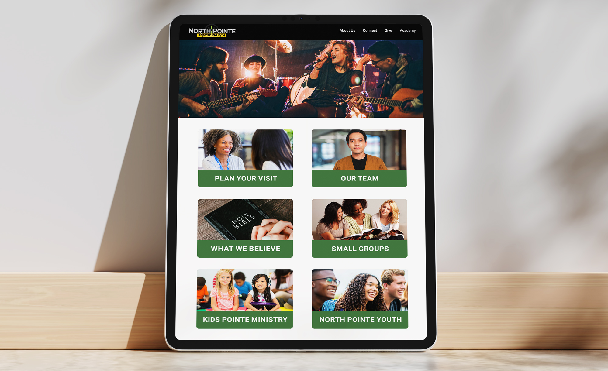 Tablet screen showing church homepage navigation grid with call-to-action cards for Plan Your Visit, Our Team, and Ministries.